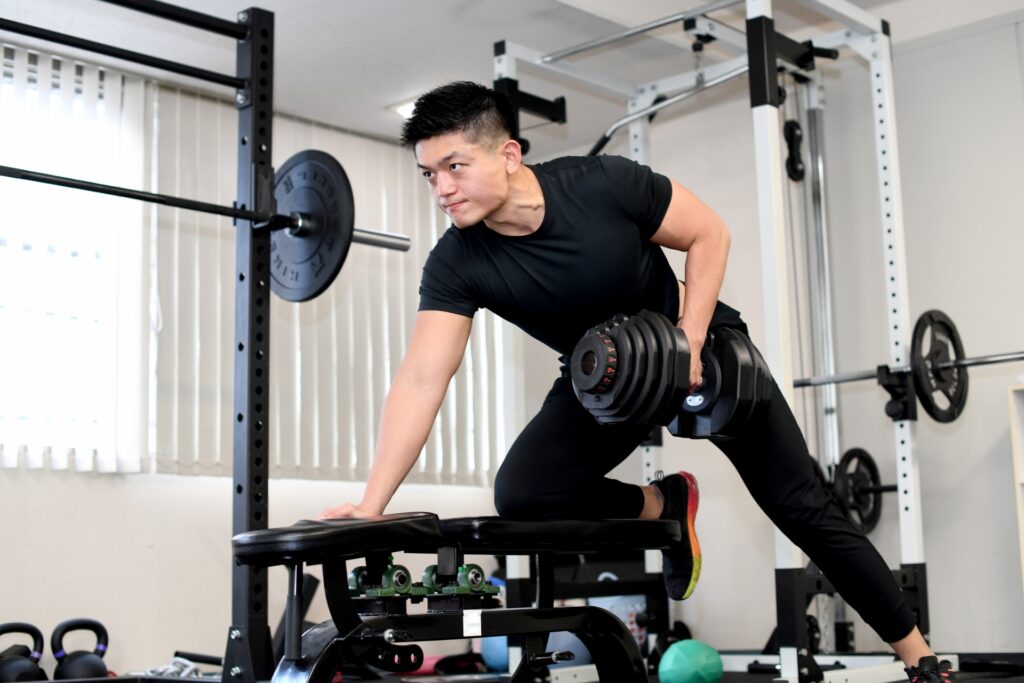 ジムでダンベルを使ってトレーニングする男性