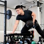Tシャツとロングパンツでジムのトレーニングをする男性