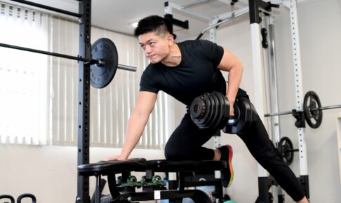 Tシャツとロングパンツでジムのトレーニングをする男性